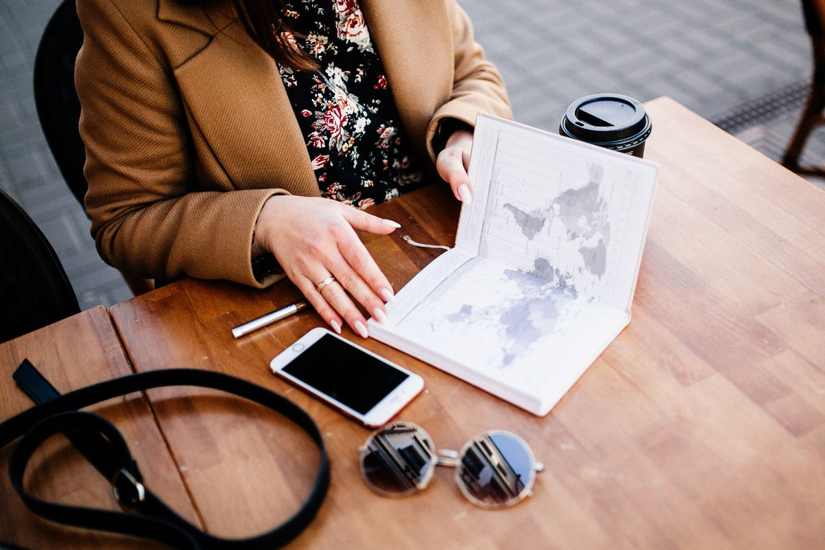 Travel designer planning a journey with a map at a cafe table